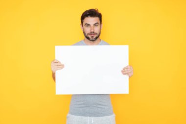 Stüdyonun arka planında boş tahtası olan yakışıklı bir adam. Telif uzayı ile boş tabela gösteren bir adam. Fikir teklifi. Reklamınız. Metin için boş alanı olan boş reklam panosu, modelle