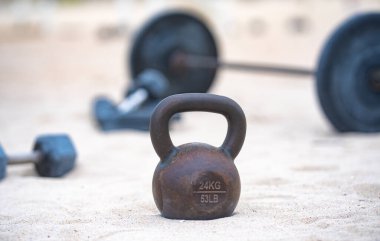 Kettlebell ve ağırlık arka planı. Ağır ağırlıklarla vücut geliştirme. Dambıllarla park egzersizi. Ağırlıklarla spor sahnesi. Kettlebell, halterler ve halterler. Ağırlık çalışması.