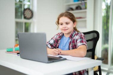 Kid preparing for exam with laptop. Student sitting at desk during distance education class. Smart child in virtual schoolwork and study. Child learning mathematics on laptop in home classroom
