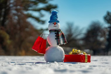 Hediye kutusu olan bir kardan adam. Tatilleri kutlayan kardan adam. Alışveriş torbalı kardan adam. Noel hediyesi fikirleri. Kış indirimli kardan adam. Kardan adam Noel alışverişi