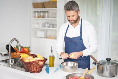 Taze sebze pişiren bir şef. Ev yapımı yemek pişiren bir adam. Mutfakta sağlıklı bir kahvaltı için sebze pişiren bir aşçı. Üniformalı şef modern bir mutfakta sebze pişiriyor.