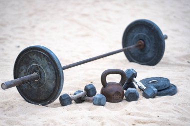 Açık spor salonu geçmişi. Kumun üzerinde metal bir çaydanlık. Açık spor salonunda sakız. Doğal antrenman. Spor salonu ağırlıkları arka planı. Yaz eğitimi geçmişi. Halter ve halter arkaplanı