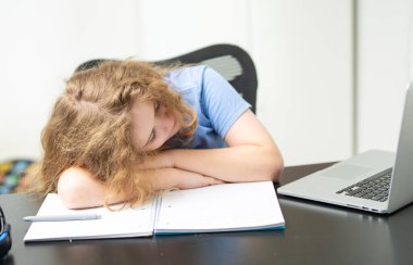 Okul masasındaki uykulu, sıkılmış çocuk. Ders çalışmaya ara vermek isteyen uykulu bir öğrenci. Uykulu kimlik, dizüstü bilgisayarın başında otururken esniyor. Uykulu çocuk çalışma yorgunluğu sıkıldı. Sıkıntıdan patlayan çocuk