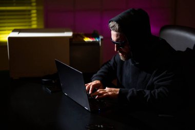 Kişisel bilgi güvenliği hackleniyor. Şifreli veri hackleme. Şifreli para için hackleme. Kripto para birimi hack konsepti. Kapüşonlu, karanlık gece temalı bir bilgisayar korsanı. Korsanlar saldırıyor
