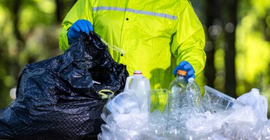 Gönüllüler atık parkları temizler. Eller gezegeni korumak için plastik şişeleri topluyor. Plastik çöpler çevreye zarar verir