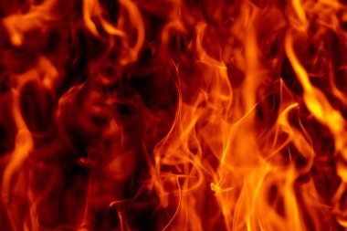 Siyah üzerine alev alev yanan doku. Parlayan ışıkla parlayan kıvılcımlar. Alevler soyut formu yakıyor. Alev görsel efekt