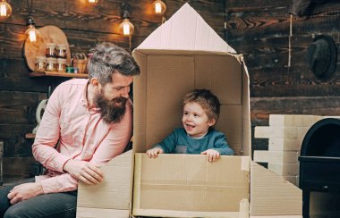 Baba ve oğul evde karton roketle oynuyorlar. Baba ve çocuğun hayal gücü. Babalık kavramı. Baba ve oğul birlikte. Baba ve oğulla ebeveyn olmak. Aile baba ve oğulla yaratıcı oyun