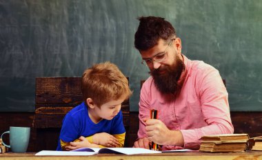 Babası evde eğitim masasında çocuk öğretmenliği yapıyor. Babam öğrenme ve çizim konusunda çocuğa yardım ediyor. Baba ve oğullu ebeveynlik ve eğitim kavramı. Ebeveyn desteğiyle evde eğitim sahnesi