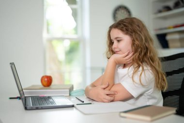 Kid preparing for exam with laptop. Student sitting at desk during distance education class. Smart child in virtual schoolwork and study. Child learning mathematics on laptop in home classroom