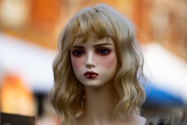 Detaylı makyajlı gerçekçi bebek portresi. Sanatsal bebek yüzlü, canlı gibi bir ifade. Sarı peruklu oyuncak bebek kafası. Görsel tasarım için gerçeküstü bebek estetiği