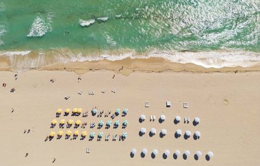 Yaz sahilindeki sahil manzarası. Kumsal manzaralı, kumlu şemsiyeli. Turkuaz okyanusta sahil şeridi. Seyahat için kumsal tatil sahnesi
