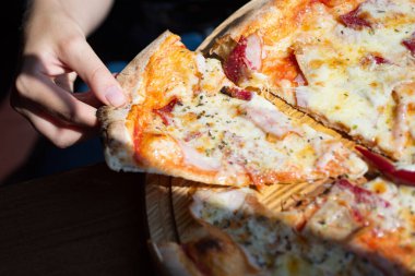 Elinde erimiş peynirle pizza. Pizza kıtır kıtır. Pizza, elinde peynirli dokularla iştahı davet eder. Pizza dilimi elinde, kapat.