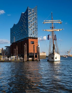 Elbphilharmonie 'nin zarif cam cephesi ve uzun gemi direkleri. Almanya 'nın turistik eğlence ve seyahat ikonu. Gemi ve mimarinin birleşiminden oluşan güzel bir şehir manzarası. Elbe Filarmoni Salonu