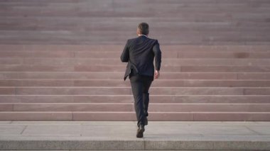 İş adamı başarıya koşar. İş adamı merdivenlerde stratejik bir adım atıyor. İşadamı basamakları aşarak merdivenleri çıkıyor. İşadamı her adımda merdivenleri çıkıyor.
