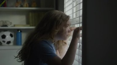 Çocuk pencere kenarında duruyor. Çocuk hayatı gözlemliyor. Çocuk duygusal bir an yaşıyor. Sessizlikte yansıyan çocuk