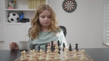 Çocuk evde satranç oynuyor. Çocuk satranç hamlesine konsantre oluyor. Çocuk satrançla strateji öğreniyor. Satranç oynarken çocuk düşüncesi