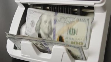 100 dolarlık banknotlarla birlikte nakit sayma işlemi. Para akışıyla bankacılık ve finansman. Bankada çalışan bir hesap makinesi. Bankacılık sistemi para işliyor. Hareket halindeki parayı saymak