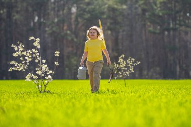 Çocuk bahçeye bir ağaç dikti. Çocuk kürek ve bitki ağacıyla toprak kazıyor. Çocuk bahçıvan meyve ağaçlarıyla ilgileniyor. Çocuklarla ağaç dikmek. Yeşil için çocuk bitkisi. Çocuklar için bahçe işleri. Çocukluk gelişimi