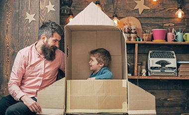 Baba ve oğul evde karton roketle oynuyorlar. Baba ve çocuğun hayal gücü. Babalık kavramı. Baba ve oğul birlikte. Baba ve oğulla ebeveyn olmak. Aile baba ve oğulla yaratıcı oyun