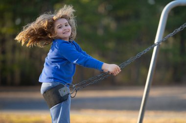 Salıncaktaki çocuk. Çocuk bahçesinde mutlu bir çocuk. Kaygısız çocuk dışarıda sallanıyor. Mutlu çocuklar dışarıda oynuyor. Sarışın çocuk mutluluktan uçuyor. Dışarıdaki oyuncu çocuk. Çocuk suratı. Mutlulukla sallanan çocuk