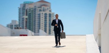 Zengin iş adamı dışarıda dolaşıyor. Çantası olan başarılı bir iş adamı. Şirket lideri harekete geçti. İş adamı güvenle yürüyor. İşadamı işe gidiyor. Takım elbiseli yakışıklı iş adamı.