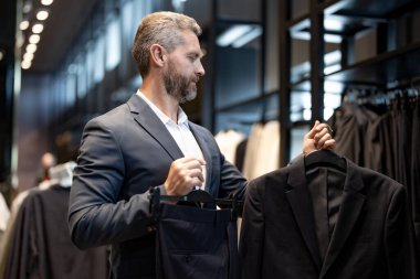 Klasik takım elbise. İspanyol bir işadamı iyi terzilikten ve takım elbiseden hoşlanır. İyi giyimli bir erkek model bir butikte poz veriyor. Perakende satış elemanı şık bir adamın mükemmel takımı bulmasına yardım eder.