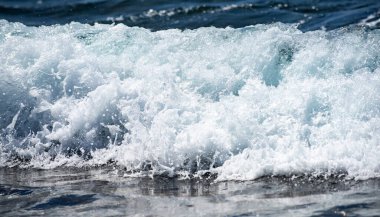 Okyanus enerjili köpüklü deniz dalgası. Tropik güneş ışığında deniz dalgaları. Kristal dalga ışığı yansıtır. Deniz dalgaları kıyıda kıvrılır ve kırılır