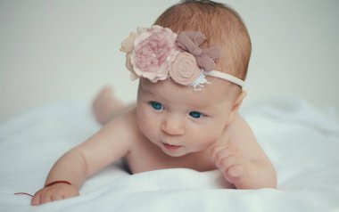 Evdeki yumuşak beyaz battaniyeye uzanmış şirin bir bebek. Mutlu bebek bağları. Yeni doğmuş yüz. Bebek yüzlü. Yatakta bebek portresi