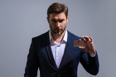 Gri izole arka planda kredi kartıyla takım elbiseli bir iş adamının portresi. Para yönetimi ve kredi puanı. Ödül parası. Kredi limiti. İnternetten alışveriş konsepti. Kredi geçmişi