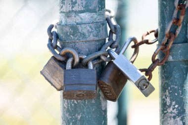 Metal bir kapıyı koruyan güçlü bir kilit. Zincirler güvenlik korumasını gösteriyor. Yıpranmış kilit, kısıtlı erişim ve güvenliği simgeliyor. Kilit detay koruma ve denetimi