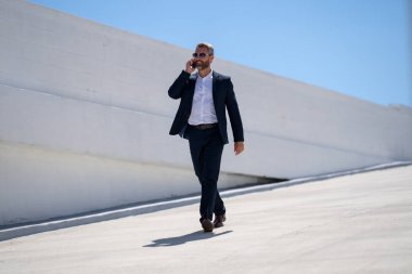 İş adamı dışarıda telefonla konuşuyor. Telefon görüşmesinde başarılı bir adam. İş adamı dışarıyı arıyor. Cep telefonu olan yakışıklı bir iş adamı. Cep telefonundan konuşan kendine güvenen bir adam. Çevrim içi iş