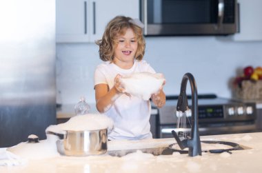 Çocuk bulaşıkları köpükle yıkıyor. Çocuk mutfakta köpükle oynuyor. C-Komik Çocuk ev işlerini seviyor. Oyuncak çocuk mutfak malzemelerini yıkıyor. Mutfakta sabun köpüğü içinde bir çocuk. Çocuk temizliğe yardım ediyor.
