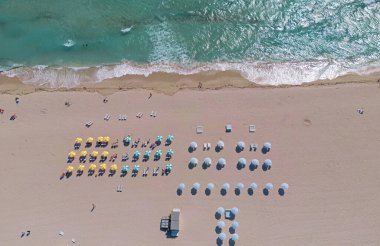 Yaz sahilindeki sahil manzarası. Kumsal manzaralı, kumlu şemsiyeli. Turkuaz okyanusta sahil şeridi. Seyahat için kumsal tatil sahnesi