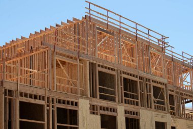 İnşaat, mavi gökyüzüne karşı ahşap iskelet gösteriyor. İnşaat binası. İnşaat, yükseldikçe yapısal ayrıntıları gözler önüne seriyor. Yapı çerçevesi ile modern gelişimi tanımlar