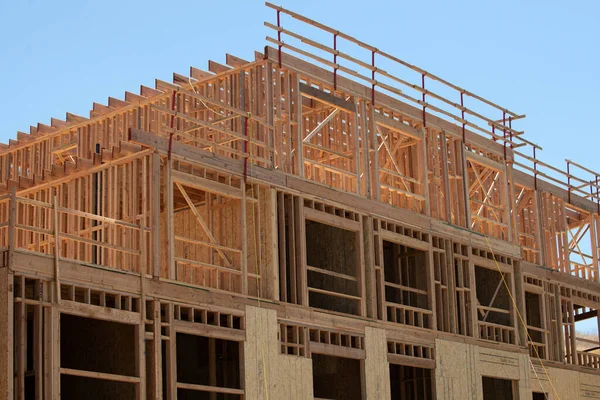 İnşaat, mavi gökyüzüne karşı ahşap iskelet gösteriyor. İnşaat binası. İnşaat, yükseldikçe yapısal ayrıntıları gözler önüne seriyor. Yapı çerçevesi ile modern gelişimi tanımlar