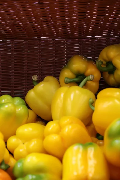 Yellow peppers in flat-bottom basket — Stock Photo, Image