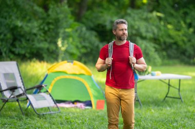 Adam doğada kamp yapmayı seviyor. Kamp gezisi. Yürüyüşten sonra bir çadırda dinleniyor. Huzurlu bir kamp alanında tatil. Yazın piknik. Açık hava macerasının özgürlüğü. Erkek kampı ve rahatlama