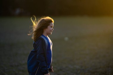 Hareketli bir çocuk, enerji dolu. Koşan çocuklar gün ışığında oynuyorlar. Neşeli koşucu dışarıda egzersiz yapıyor. Küçük koşucu, koşmanın eğlencesi. Çimenli bir arazide yarışan çocuk