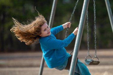 Sarışın çocuk dışarıda sallanıyor. Salıncakta gülen çocuk. Oyun bahçesinde oynayan sevimli çocuk. Heyecanlı çocuk salıncakta sallanıyor. Yaz parkındaki sevimli çocuk. Parkta sallanan oyuncu çocuk. Mutlu çocukluk