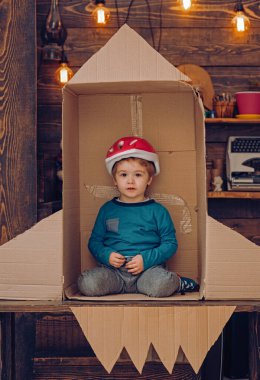 Karton bir roketin içinde oynayan bir çocuk. Çocuk hayal gücü. Çocuk hayal gücüyle uzayda uçuyor. Hayal gücünüz için yaratıcı bir oyun çocuklar. Çocukluk hayalgücü. Oyuncak roketli çocuk yaratıcılığı