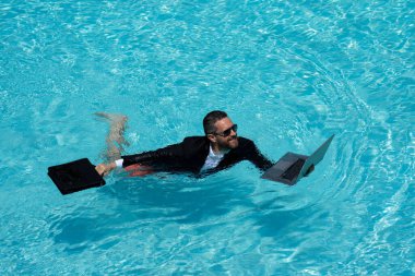 Takım elbiseli çılgın iş adamı havuzda dizüstü bilgisayar kullanıyor. Bilardoda çalışan çılgın bir serbest yazar. Deniz sahilinde dizüstü bilgisayarı olan komik bir iş adamı. Yaz seyahati ve plaj. Yaratıcı çevrimiçi strateji