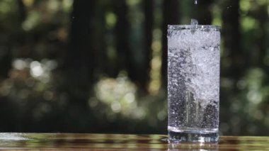 Temiz bir bardağa tatlı su dökülüyor. Bardağı dolduran temiz su. Bardakta köpükler olan saf içme suyu. Su yavaşça şeffaf cama dökülüyor.