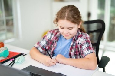 Child learning online with laptop at home. Kid studying using laptop in classroom. Kid student doing homework during online lesson. Kid focused on laptop in homeschooling. Student at desk e-learning