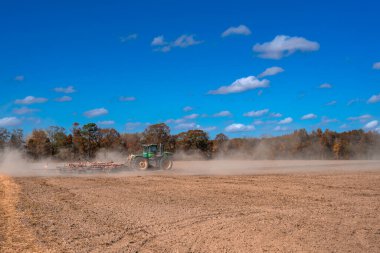 Traktör tarlayı sürüyor. Kırsalda sonbahar çiftçiliği. Kırsal tarım arazilerinde traktör. Toprakta çalışan tarım makinesi ya da traktör. Çekici tarla sürme çiftliği. Çiftlik arazisi