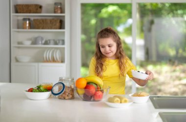 Modern mutfakta sağlıklı yiyecekler yiyen çocuklar. Modern mutfakta taze sebzelerin tadını çıkaran mutlu çocuklar. Modern mutfakta vejetaryen yemeği yiyen sevimli çocuklar. Çocuklar için modern mutfak