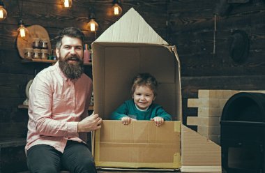Baba ve oğul evde karton roketle oynuyorlar. Baba ve çocuğun hayal gücü. Babalık kavramı. Baba ve oğul birlikte. Baba ve oğulla ebeveyn olmak. Aile baba ve oğulla yaratıcı oyun