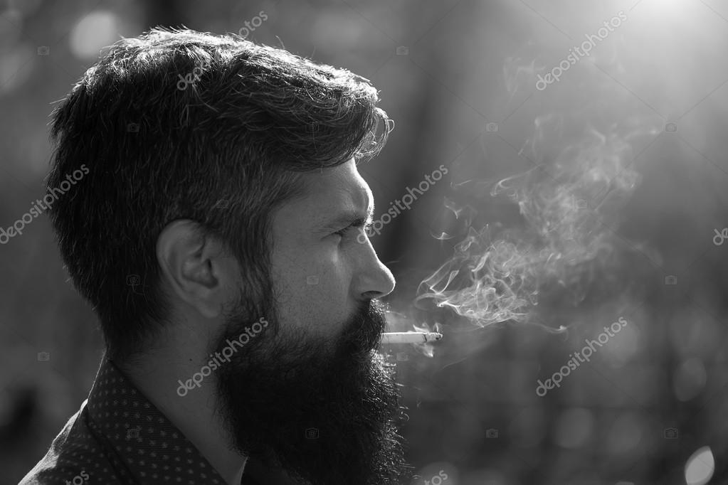 Vista de perfil de um homem bonito com cabelo loiro olhando para a câmera  ao ar livre