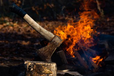 Kamp ateşinden baltayla ateş edilmiş. Baltanın yanında parlak alevler var. Baltanın yanındaki ateş baltanın ısısını arttırır. Ateş ve balta olayı dramatikleştiriyor.