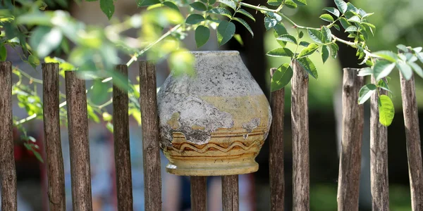 Старый глиняный горшок на заборе — стоковое фото