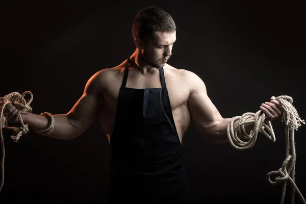 Muscular man in apron with rope — Stock Photo, Image